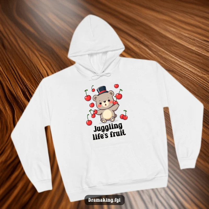 Funny Bear Hoodie depicting a whimsical bear wearing a tiny top hat and juggling oversized cherries, perfect for cozying up.